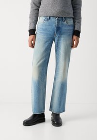 Lichtblauwe denim jeans met een recht gesneden ontwerp, voorzien van vervagingdetails en vijf zakken, gedragen met zwarte enkelboots.