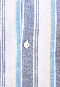Camisa de botones a rayas con rayas azules, amarillas y blancas sobre una tela clara. Un solo botón blanco se muestra en el área del pecho.