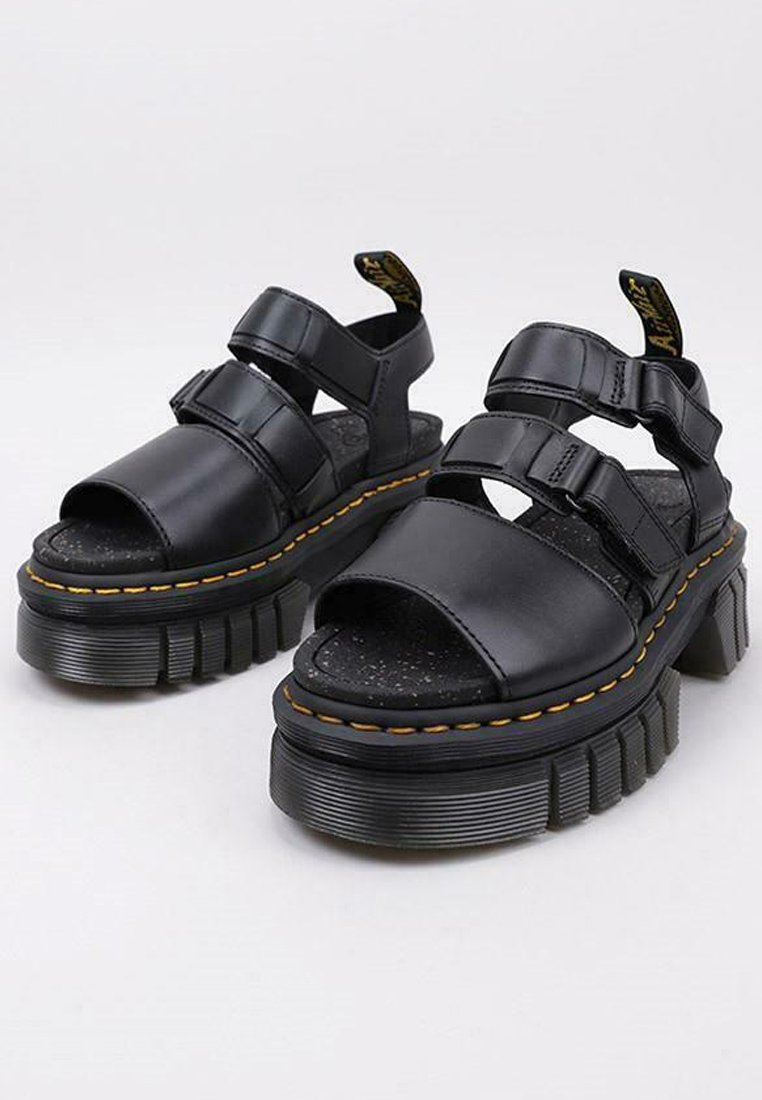 Sandalias de plataforma negras hechas de cuero suave, con tres correas ajustables, plantilla texturizada y costuras amarillas en una suela gruesa.