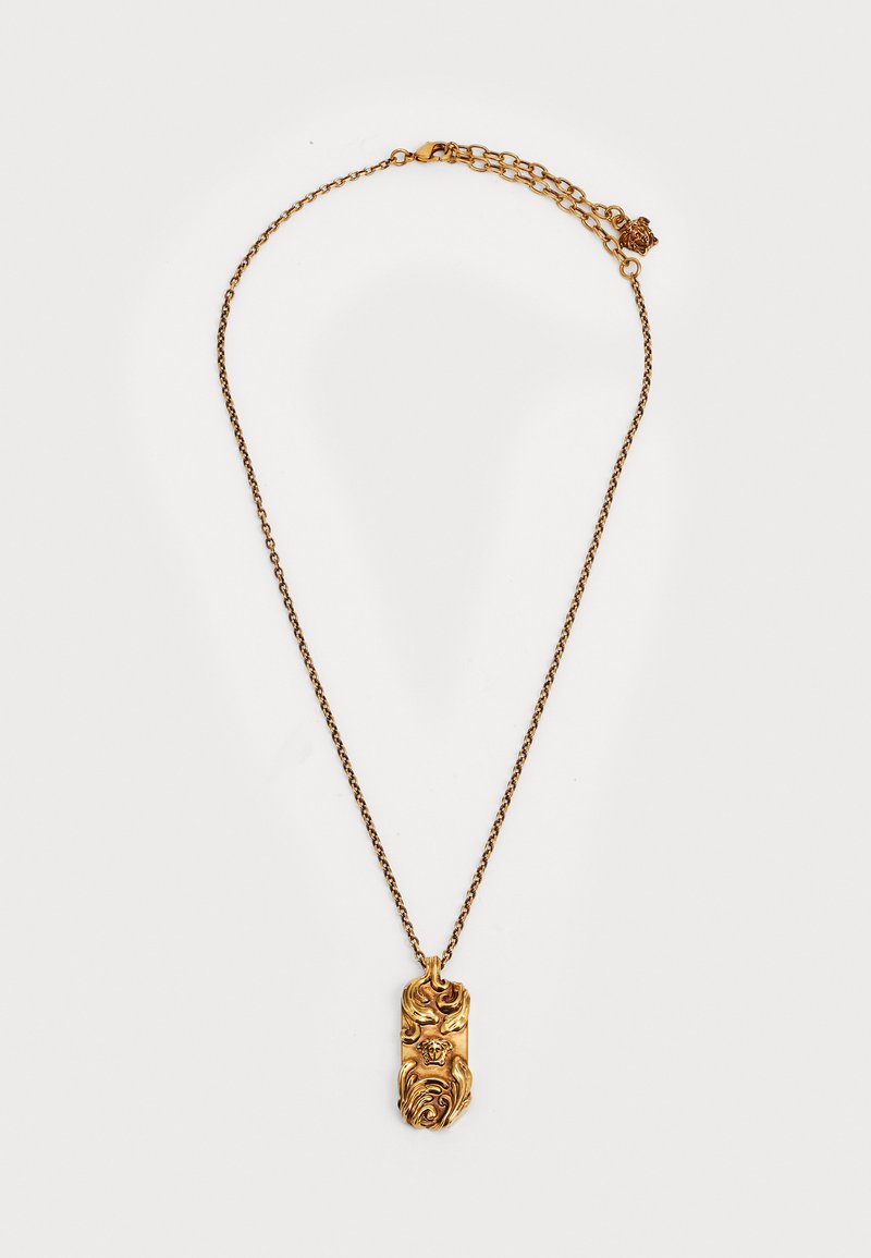 Collana con pendente d'oro su una catenina sottile, caratterizzata da un ciondolo dettagliato e testurizzato con motivi vorticosi e un gancio.