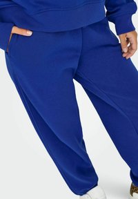Royal blue dresowe spodnie wykonane z miękkiego, teksturowanego materiału. Cechy to elastyczny pas, boczne kieszenie oraz ścięgno przy nogawkach.