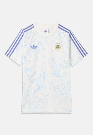 Maglia sportiva bianca a maniche corte con motivo a spirale azzurro chiaro, strisce viola Adidas sulle spalle e stemma dell'Associazione Calcistica Argentina.
