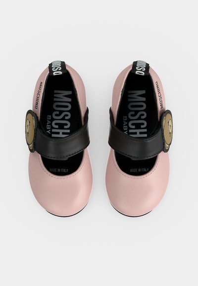 Chaussures bébé roses avec des brides noires présentant des visages d'oursons et le logo Moschino à l'intérieur et sur les brides.