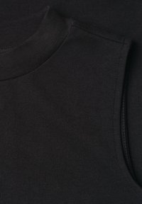 Gros plan d'un haut noir sans manches montrant l'encolure ronde et la texture du tissu.