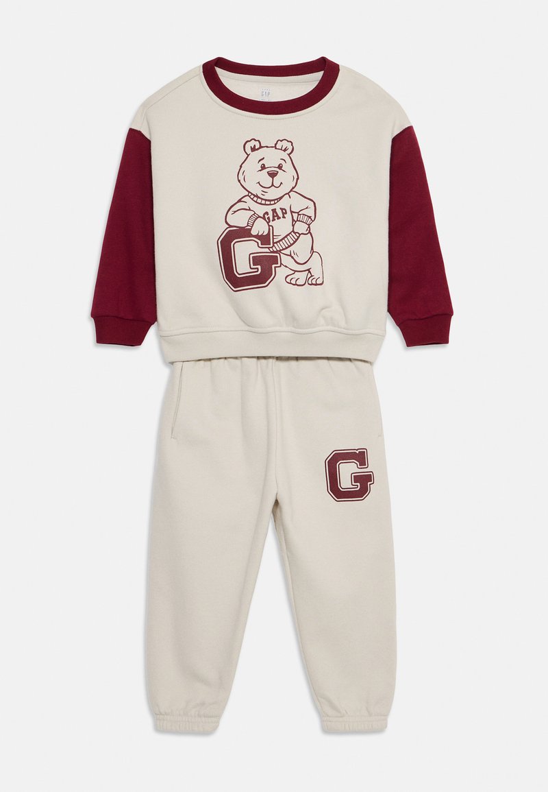 Baumwolle-Loungewear-Set mit einem cremefarbenen Oberteil und burgunderfarbenen Ärmeln. Mit einem Bärenmotiv und dem Text 'GAP' auf dem Oberteil; 'G'-Logo auf den Hosen.