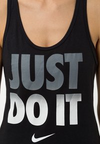 Schwarzes Tanktop mit einem Rundhalsausschnitt, versehen mit großem grauem und weißem Text "JUST DO IT" sowie einem kleinen Nike-Swoosh-Logo am unteren Rand.