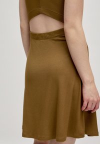 Braun geripptes Kleid mit tailliertem Oberteil und ausgestelltem Rock. Besitzt ein Cut-Out-Detail am Rücken und eine glatte Textur.