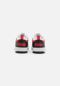 Svartvita sneakers med röda accenter, med en texturerad ovandel, vadderad krage och en framträdande "PUMA"-logotyp på hälen.