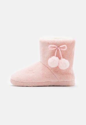 Chaussons bottes en peluche rose avec une texture douce, dotés d'une doublure en fausse fourrure, d'accents pompon et d'un motif étoile cousu.