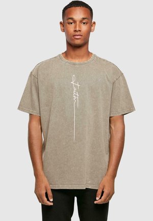 Korte ærmer, oversized t-shirt i dæmpet taupe med en hvid kursiv "Faith" grafik på forsiden; bomuldsstof med en blød tekstur.