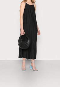 Černé plisované maxi šaty s halter krkem, doplněné světle modrými sandály na blokovém podpatku a prošívanou černou kabelkou.