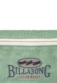 Zielona torba z kordurowego materiału z białym zamkiem, z haftowanym logo "Billabong" oraz wzorem fal w kolorze granatowym i brązowym, z napisem "since 1973."