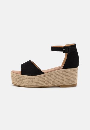 Sort platformsandal med ankelrem og spænde, med flettet jutesål og peep-toe design.