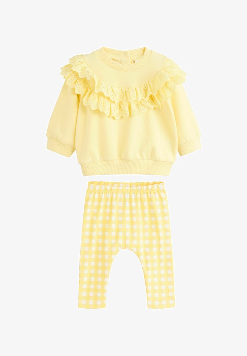 Gelbes Sweatshirt mit einem rüschigen Spitzenkragen und langen Ärmeln, kombiniert mit karierten gelben Hosen. Beide Teile bestehen aus weichem Material.