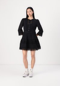 Must must dress pikade varrukatega, pitsdetailidega, nööbivarr front ja laienev seelik. Kantud valgete kõrge säärega tossudega. Sile kangastekstuuri.