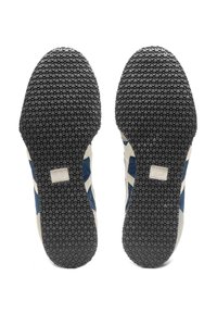 Niebieskie i kremowe buty sportowe z teksturowaną czarną gumową podeszwą z wzorami zapewniającymi przyczepność oraz białym paskiem akcentującym po bokach.