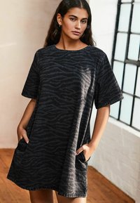 Robe en denim noir avec un motif zèbre, manches courtes, col rond et poches latérales. L'ourlet présente des détails de couture visibles.