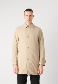 Beige esőkabát, gallérral, gombos záródással és oldalsó zsebekkel. Simaságú anyag és testhezálló fazon, két gombbal a mandzsettákon.