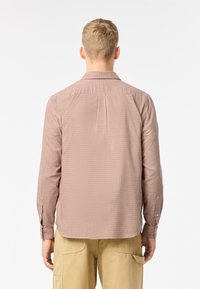 Camisa de cuadros rojos y blancos, de botones, con mangas largas, detalle de pliegue en la parte posterior, botón único en los puños, tejido suave, corte casual.