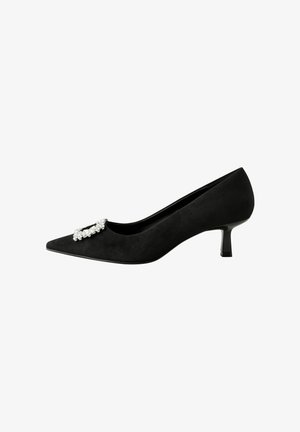 Schwarze Wildleder-Pumps mit spitzem Zehenbereich, Kitten-Heel und mit Edelsteinen besetztem Riemen auf dem Vorderblatt. Glatte Textur und schlanke Silhouette.