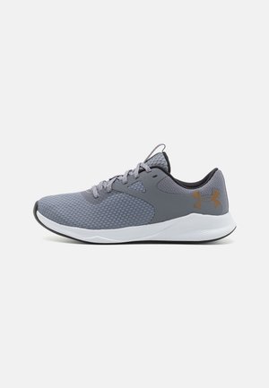 Grauer Mesh-Sportschuh mit weißer Sohle, Schnürdesign, schwarzer Innenausstattung und orangefarbenem Under Armour-Logo an der Ferse.