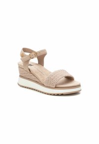 Sandalo con tacco a cuneo beige, caratterizzato da una fascia intrecciata, fibbia alla caviglia, materiale morbido simile alla pelle scamosciata, fondo testurizzato e una suola intermedia bianca con un accento marrone.