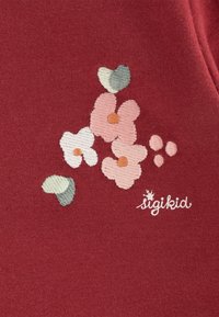 Roter Stoff mit gesticktem Blütendesign, das pinke und weiße Blumen sowie grüne Blätter zeigt und mit einem "sigikid"-Logo akzentuiert ist. Glatte Textur.