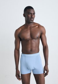 Lichtblauwe katoenen boxershorts met een witte Calvin Klein-logo op de tailleband, met een strakke pasvorm en een gladde textuur.