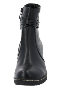 Botín negro de tobillo hecho de cuero sintético liso. Cuenta con una cremallera lateral, una correa decorativa, punta redondeada y costuras blancas en contraste.