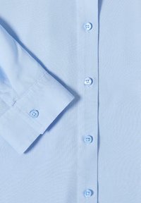 Chemise bleu clair avec poignet boutonné et rangée de boutons assortis sur le devant au centre.