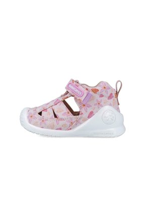 Zapato infantil rosa claro con patrón floral, que presenta recortes, una correa ajustable y suela de goma blanca para transpirabilidad y soporte.