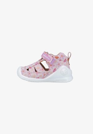 Zapato infantil rosa claro con patrón floral, que presenta recortes, una correa ajustable y suela de goma blanca para transpirabilidad y soporte.