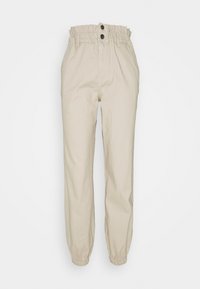 Pantalon beige taille haute avec taille élastiquée style paperbag, deux boutons noirs, poches latérales et poignets élastiques aux chevilles.