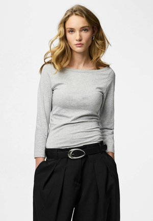 Top grigio a maniche lunghe con scollo a barca, abbinato a pantaloni neri a vita alta con cintura larga e fibbia ovale argento.