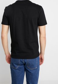 Černé bavlněné tričko s kulatým výstřihem a krátkými rukávy, s hladkou texturou a jednoduchým designem. Nosit s modrými džínami.