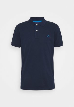 Polo bleu marine en coton, doté d'un col classique, de deux boutons et d'un petit logo bleu sur la poitrine. Manches courtes.