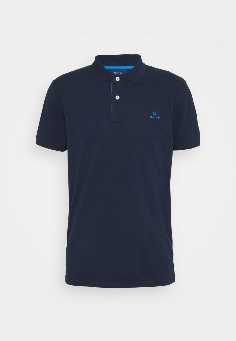 Polo bleu marine en coton, doté d'un col classique, de deux boutons et d'un petit logo bleu sur la poitrine. Manches courtes.