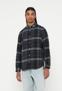 Sort og blåternet flannelsskjorte med button-down krave, lange ærmer og hvide knapper. Blød tekstur med kontrasterende mønstre.
