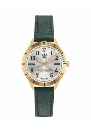 Montre analogique dorée avec un cadran argenté, un bracelet en cuir vert et des indicateurs horaires noirs. Dispose d'une lunette texturée et du logo de la marque.