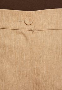 Beige trousers featuring a textured fabric, a flat waistband, and a round button detail at the front. Plain design, no patterns.