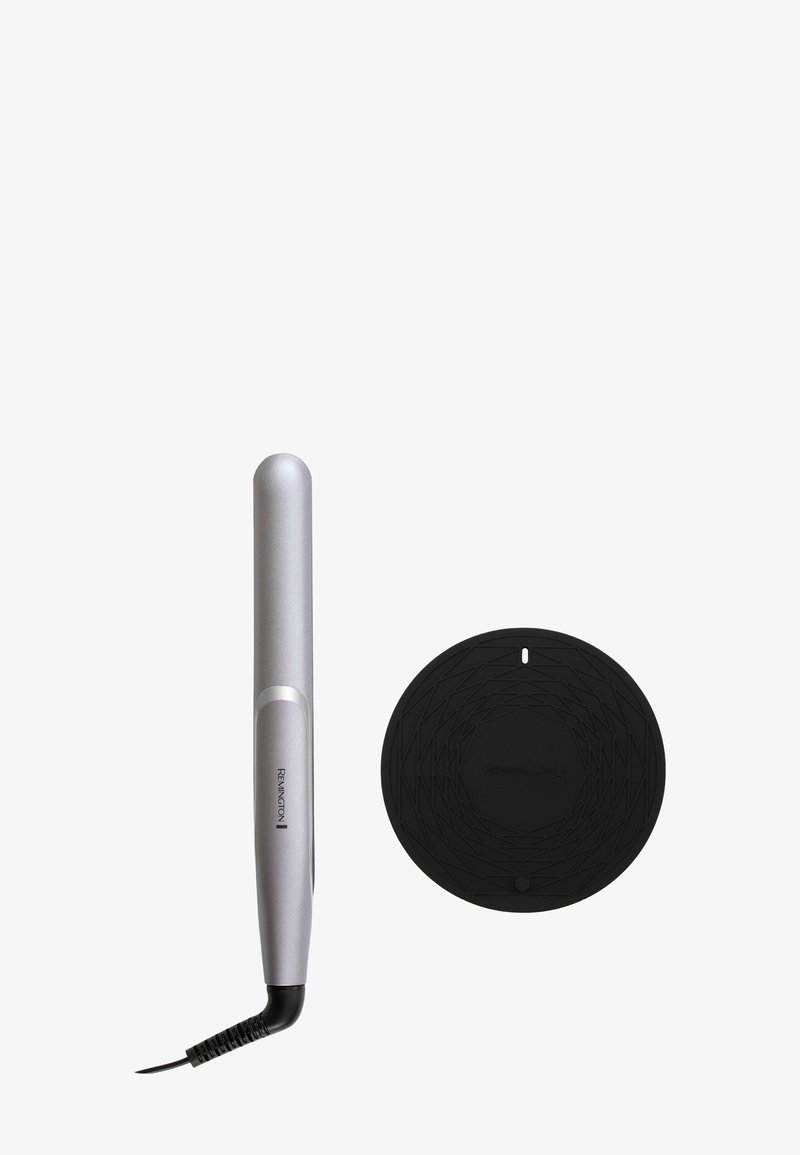 Piastra per capelli argentata e slanciata con punta arrotondata, accompagnata da un tappetino circolare nero resistente al calore con un motivo geometrico.
