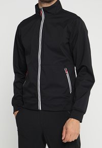 Veste noire avec fermeture éclair à l'avant, col montant et accents blancs. Comprend deux poches latérales zippées et une coupe ajustée. Texture lisse.