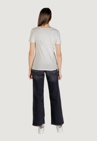 T-shirt bianco a maniche corte abbinato a jeans ampi scuri e sneakers bianche. Tessuto morbido e vestibilità comoda. Design semplice, senza fantasie.