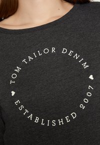 Felpa grigia scura con scollatura arrotondata. Decorata con testo bianco: "TOM TAILOR DENIM" e "ESTABLISHED 2007" disposti in un layout circolare.