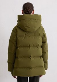 Olijfgroen pufferjack met capuchon, met een horizontaal gestikt ontwerp, dikke isolatie en elastische manchetten. De achterkant toont een ontspannen pasvorm.