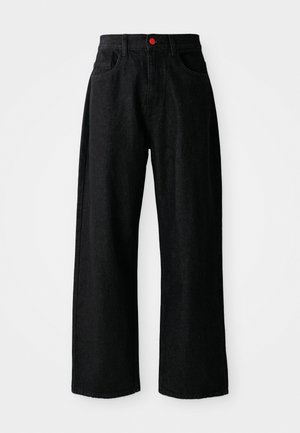 Mustadest denimist laiad püksid kõrge vöökohaga, millel on kaks eesmistTaskut ja eristuv punane nupp kinnitamiseks. Sile tekstuur.