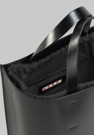 Borsa tote in pelle nera con manici robusti, dotata di un interno in tessuto grigio, rifiniture elastiche e un'etichetta visibile con la scritta "Marni".
