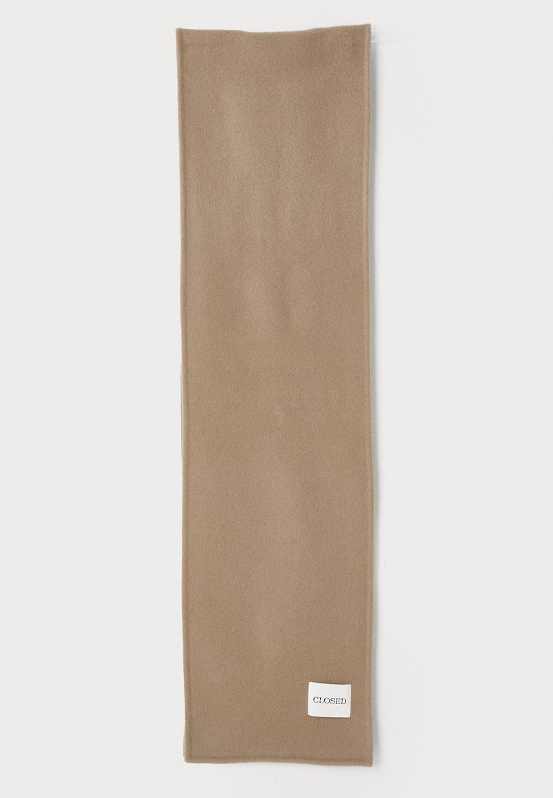 Beige uldhalstørklæde med en blød tekstur, rektangulær form og et lille hvidt mærke syet på den ene side.