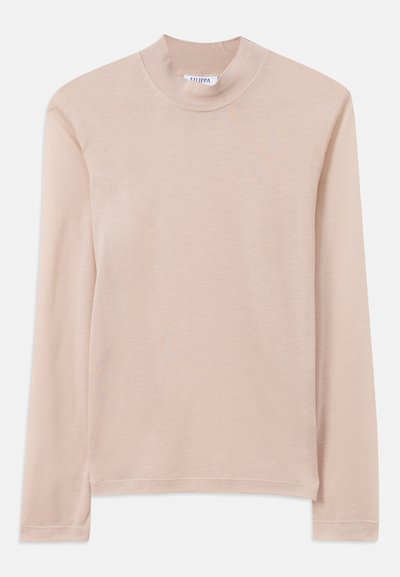 Üde rózsaszín, hosszú ujjú felső, magas nyakkal, puha anyagból készült; varrott szegéllyel és oldalsó hasítékokkal rendelkezik a szabad mozgás érdekében.