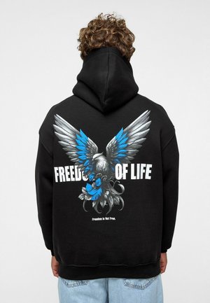 Zwarte hoodie met een adelaarsgrafiek met blauwe accenten en witte tekst "VRIJHEID VAN HET LEVEN." De tekst eronder luidt "Vrijheid is niet gratis."